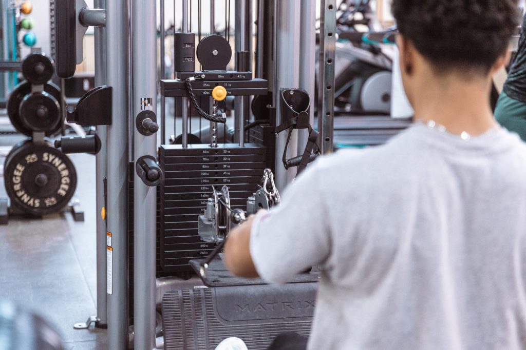 Student using equipment in college weight room.