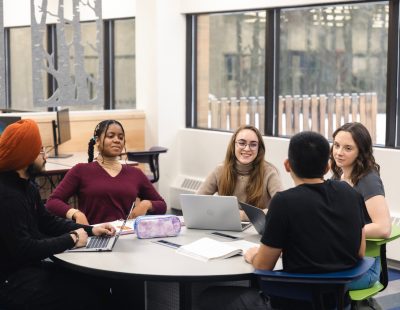 Image shows a diverse group of students around a table.