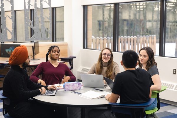 Image shows a diverse group of students around a table.