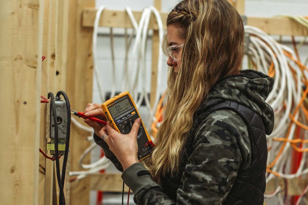 An image of a female electrician working on a circuit breaker.