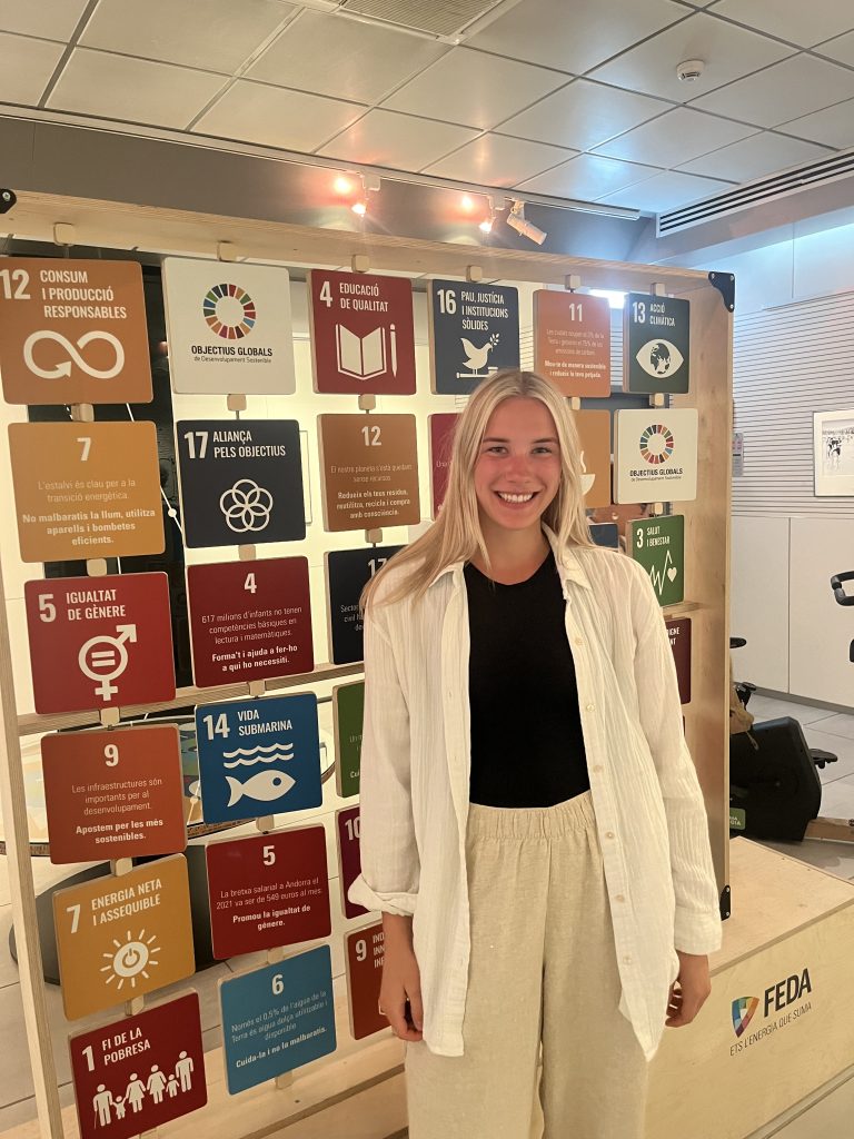 Female overseas learner posing in front of UN Sustainable Development Goals display.