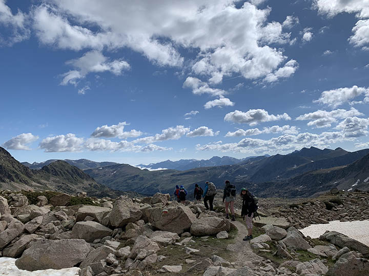 Image shows a group of people hiking atop the Pyrenees Mountains near Andorra.