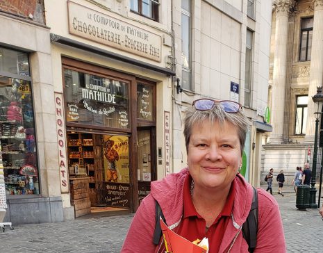 Image shows woman smiling outside french chocolate shop.