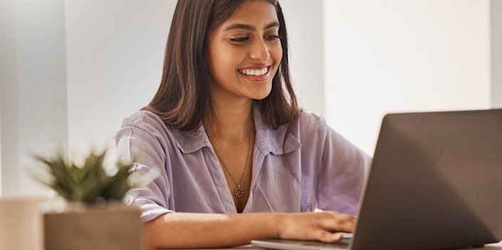 Young female student working on computer and smiling.