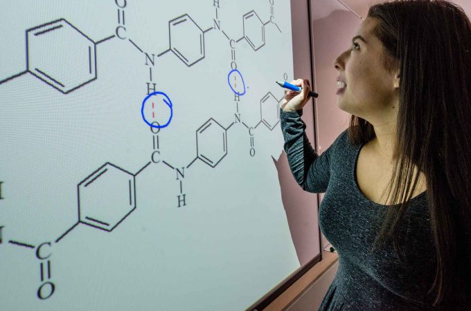 Female student looking at chemical equation on whiteboard