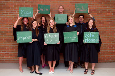 Image shows Bachelor of Education graduates holding chalkboard signs with words on them.