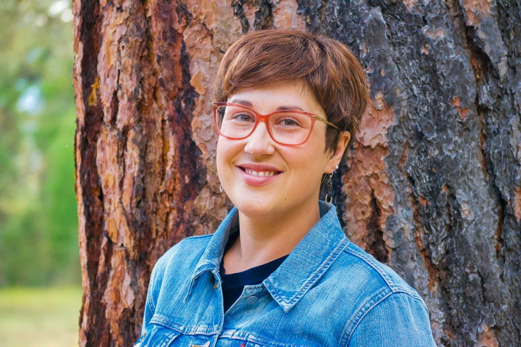 Close up head shot of instructor in front of tree in forest.