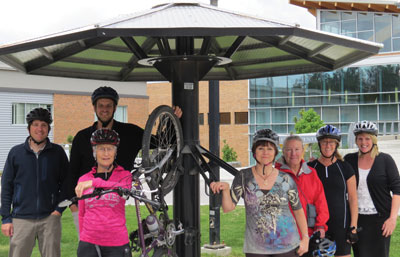 Image of seven College employees, wearing helmets, at bike rack.