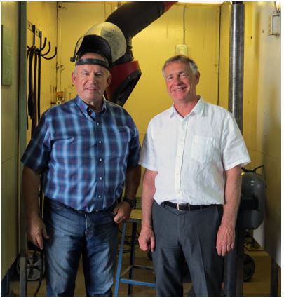 Image of East Kootenay MLA Bill Bennett, wearing a welding helment, alongside College president David Walls.