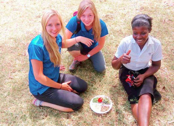 Image shows two caucasian students with a Kenyan local.