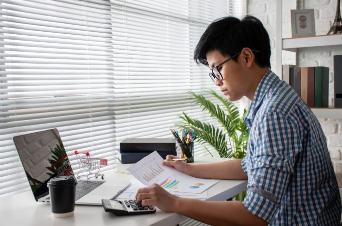 Accounting businessmen wear blue plaid shirts, calculating economic costs with a calculator in a modern office, accounting concepts.