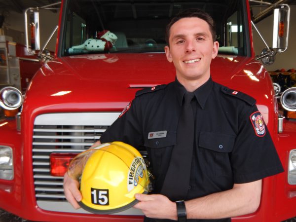 Image of man in firefighter uniform in front of fire truck.