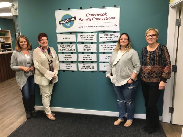 Four women stand next to Cranbrook Family Connections sign