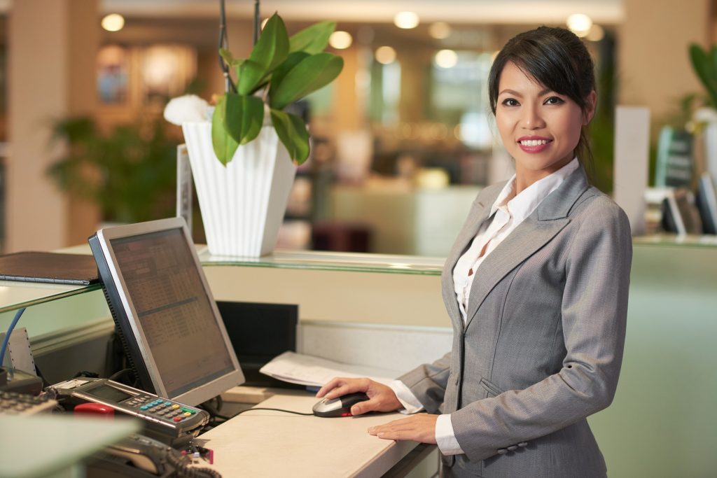 Portrait of cheerful Asian receptionist smiling and looking at camera.