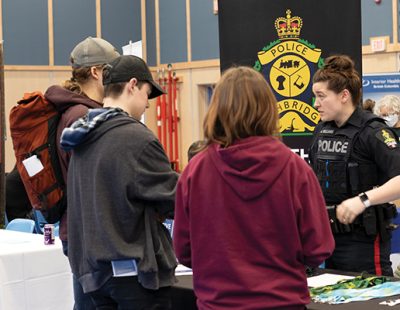 Image shows 3 young individuals speaking with a representative from the RCMP at the 2023 Career and Job Fair