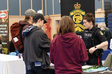 Image shows a group of potential future police officers talking to a member of the RCMP at the 2023 Career and Job Fair.