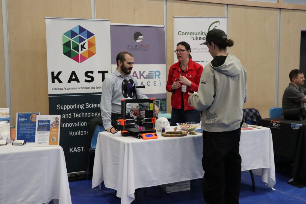 Businesses set up with tables a career fair. Male is stopped at table inquiring.