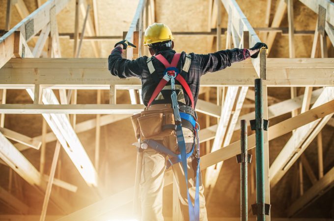 Skeleton House Frame Construction Worker Wearing Safety Harness Staying in Front on the Building and Preparing Himself For the Job.