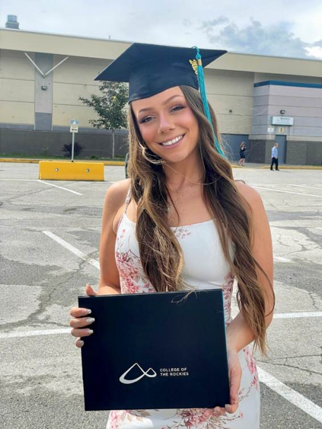 Image shows woman in grad cap holding a College of the Rockies folder with her credential.