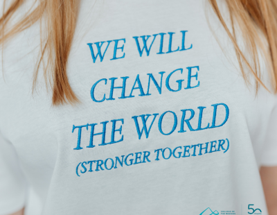 Image shows white t-shirt with teal writing saying We Will change the world (stronger together)