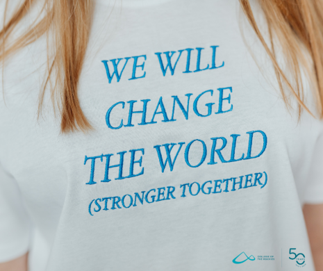 Image shows white t-shirt with teal writing saying We Will change the world (stronger together)