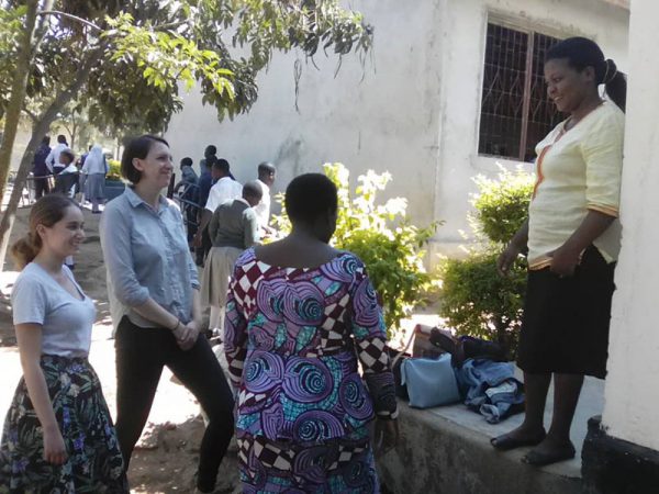 Image of two Caucasian students speaking with two Tanzanian women.