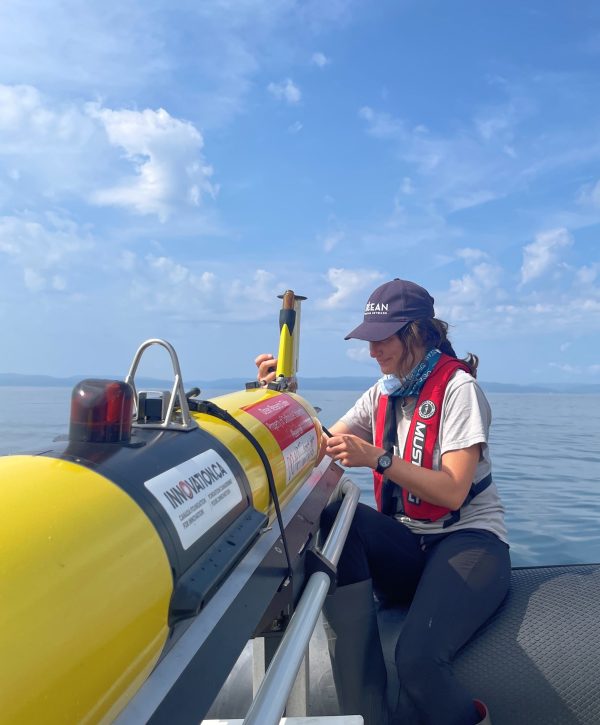 Image shows a woman on the ocean in a boat, working