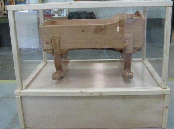 Image shows hand-crafted cradle encased in a display box.