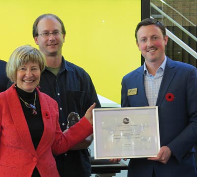 Image shows Colleges and Institutes Canada President Denise Amyot presenting an award to Graham Knipfel, Manager of International Projects as College Assistant Registrar Jason Colombo looks on.