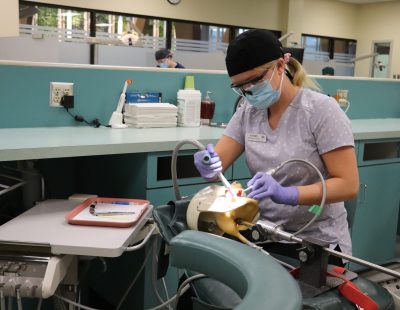 Dental student cleaning teeth on mannikin.