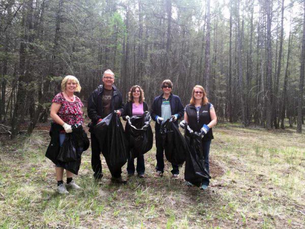 Image shows five individuals wearing gloves and holding garbage bags.