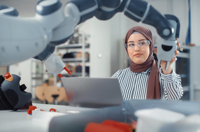 Muslim Businesswoman Working on Engineering Project, Coding on Laptop and Changing Robot Hand Position.