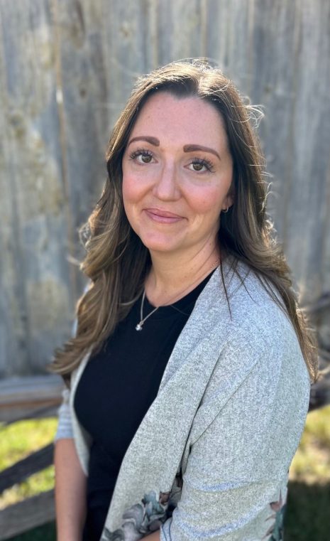 Image shows woman outdoors smiling at the camera.