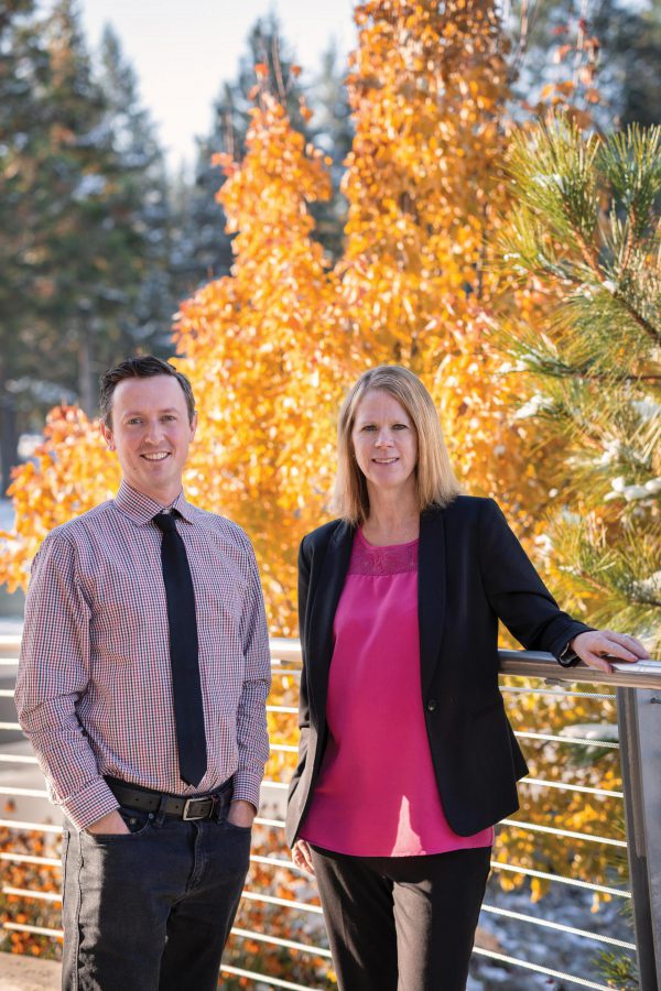 Image of man and woman standing with fall foliage behind them.