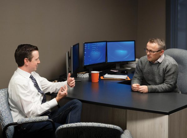 Image of two men in an office setting, conversing.