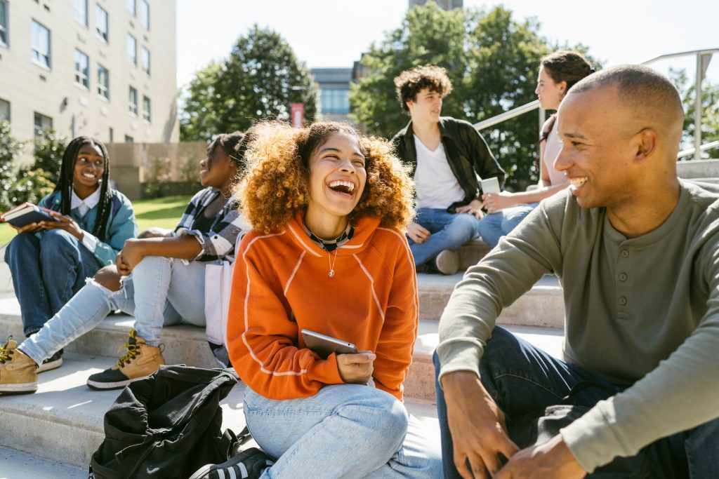 Youth worker hangs out with laughing student at entrance of school.