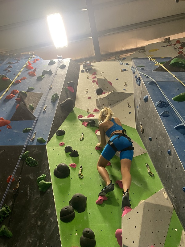 Female student climbing on a climbing wall.