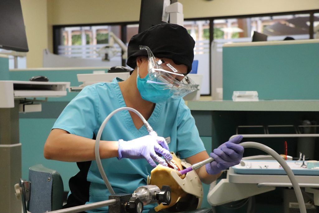 A female Dental Assistant student practicing her skills on a mannequin.