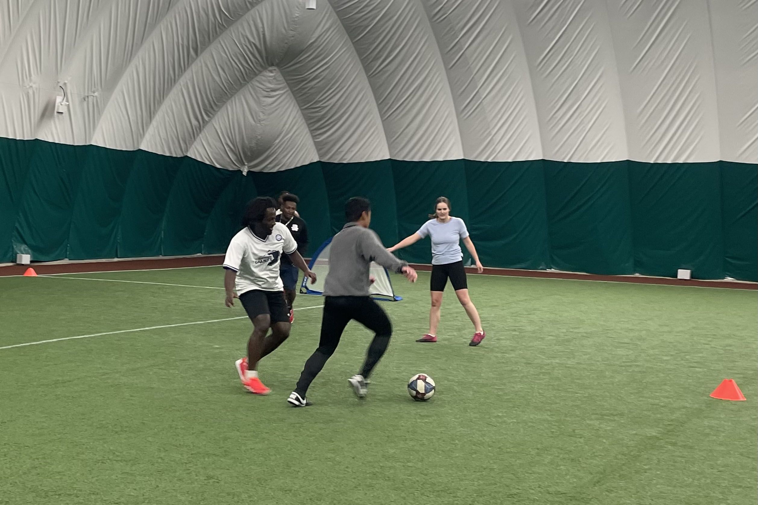 A group of college students playing indoor soccer.