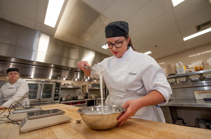 Professional Cook student stirring ingredients in mixing bowl.