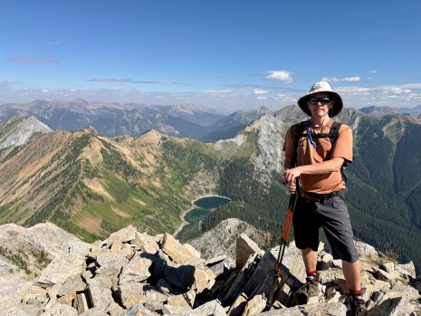 Image shows man on top of a mountain