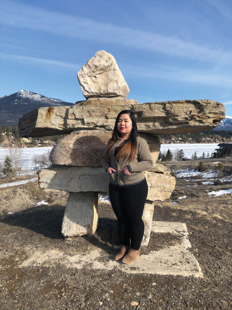 Female Hospitality Management student standing in front of a rock sculpture.