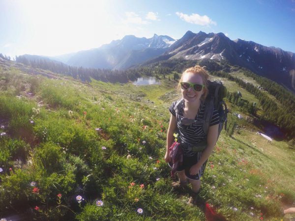 Image of smiling woman in sunglasses hiking in the mountains.