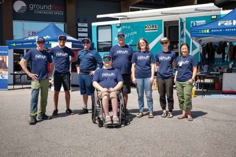 Image shows a group of people all wearing the same shirts standing outside in front of a mobile classroom.