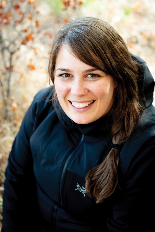 Image of smiling woman outdoors, wearing a black jacket.