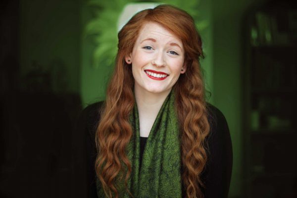 Image of red-haired woman in green scarf with a green background.