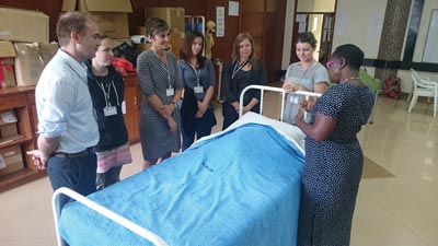 Image of College of the Rockies and Okanagan College representatives standing around a hospital bed with Dedan Kimathi University representative.