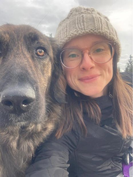 Image shows woman in toque and glasses with her dog.