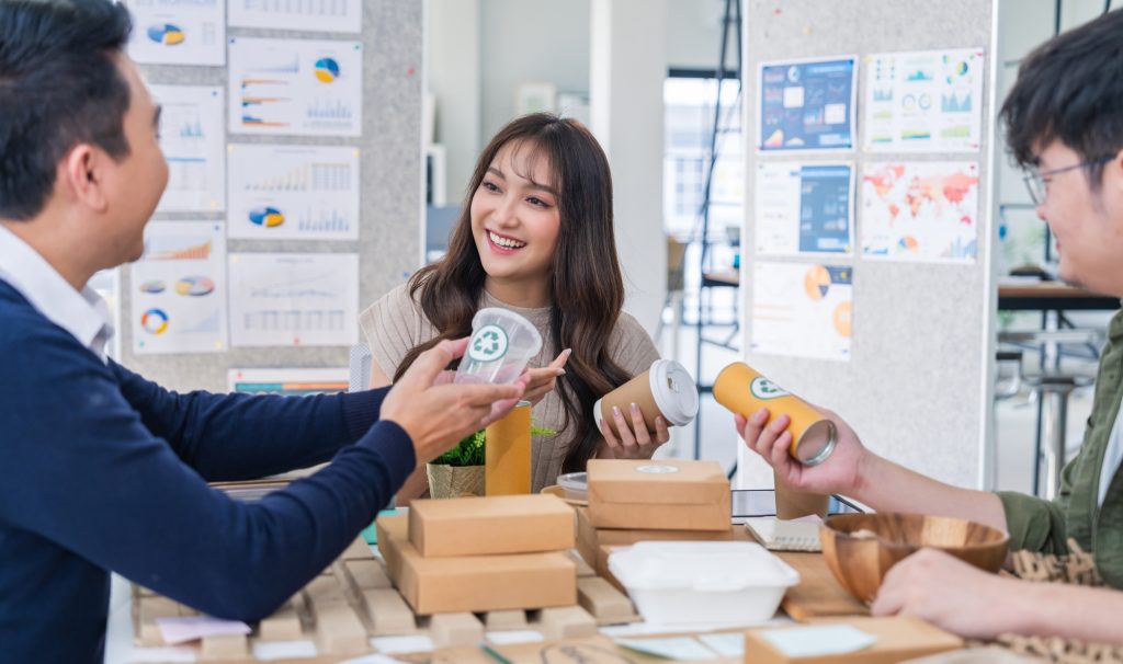 creative product design businesswoman holding various packages and recyclepaper material that she is arranging on her desk she is thinking esg project for enery green and net zero save the earth concept