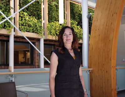 Image shows woman with long brown hair standing in the College's foyer
